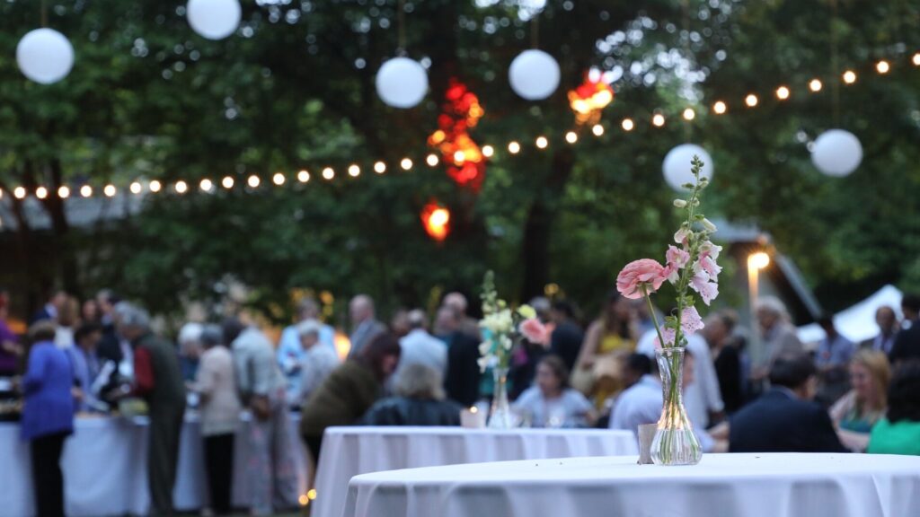 People at a party outdoors under string lights.