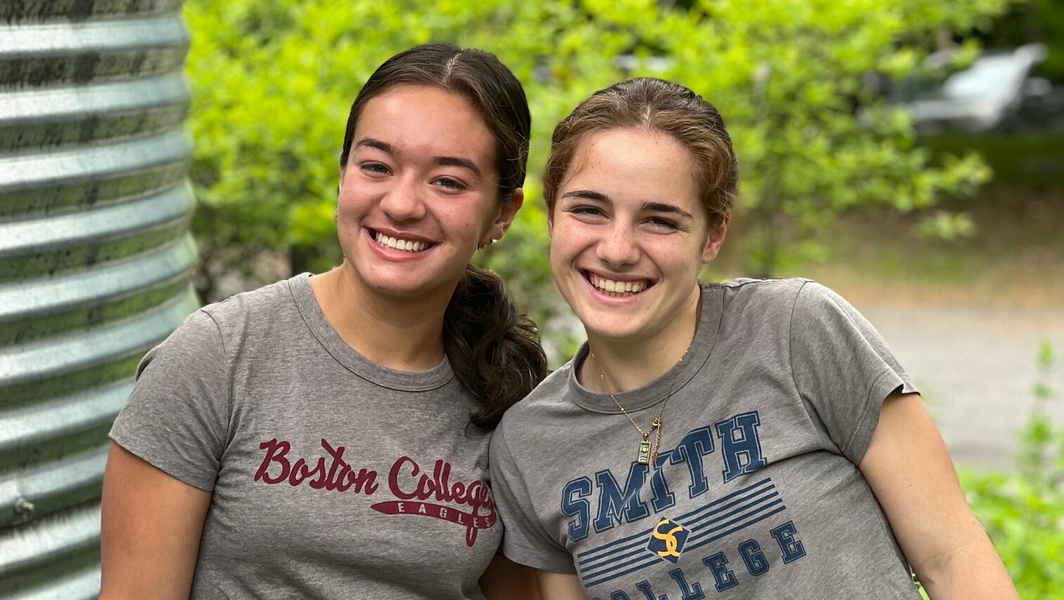 Two young women in grey college t-shirts smile in the Schuylkill Center garden.