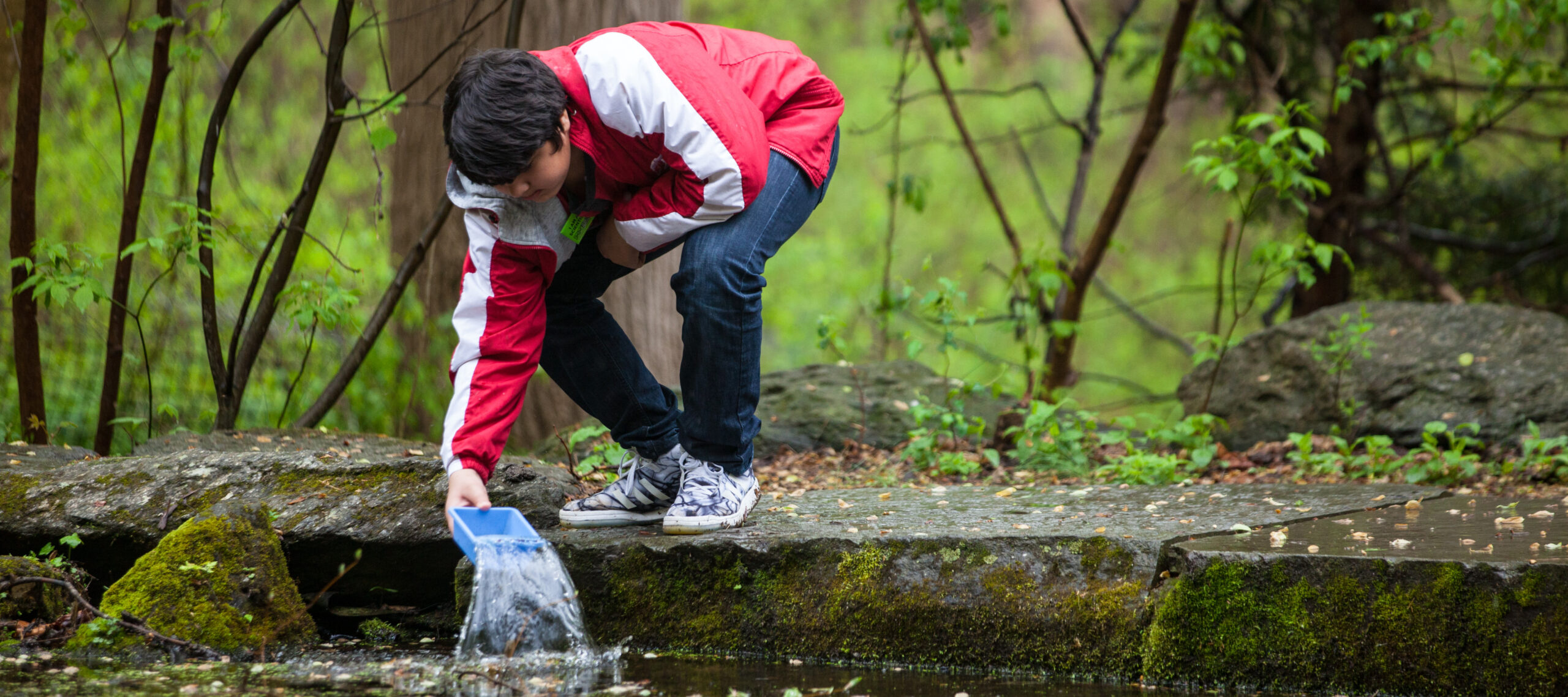 A person leans over to scoop up water in a blue box.