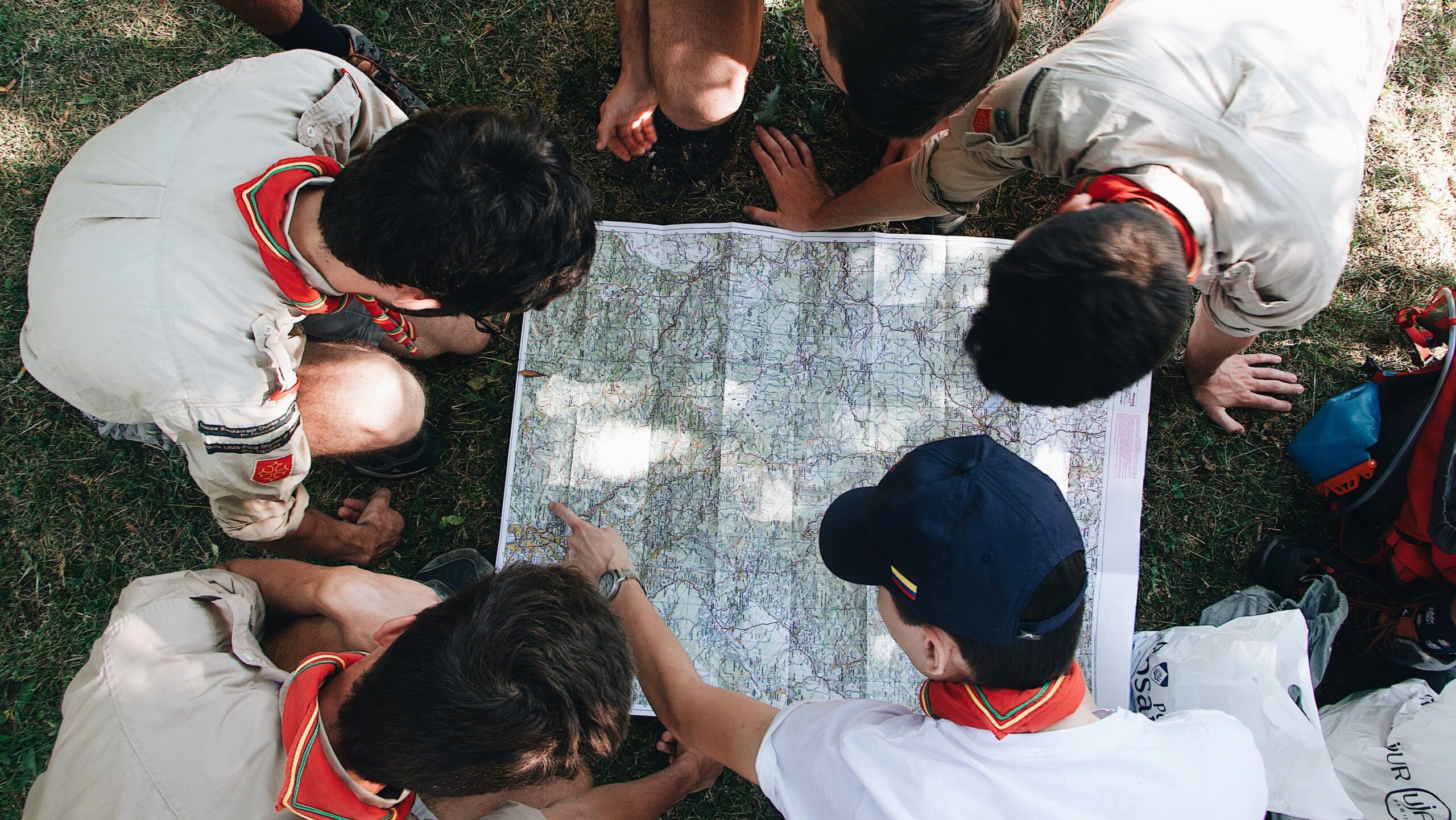 A group of scouts gather around a map outdoors.