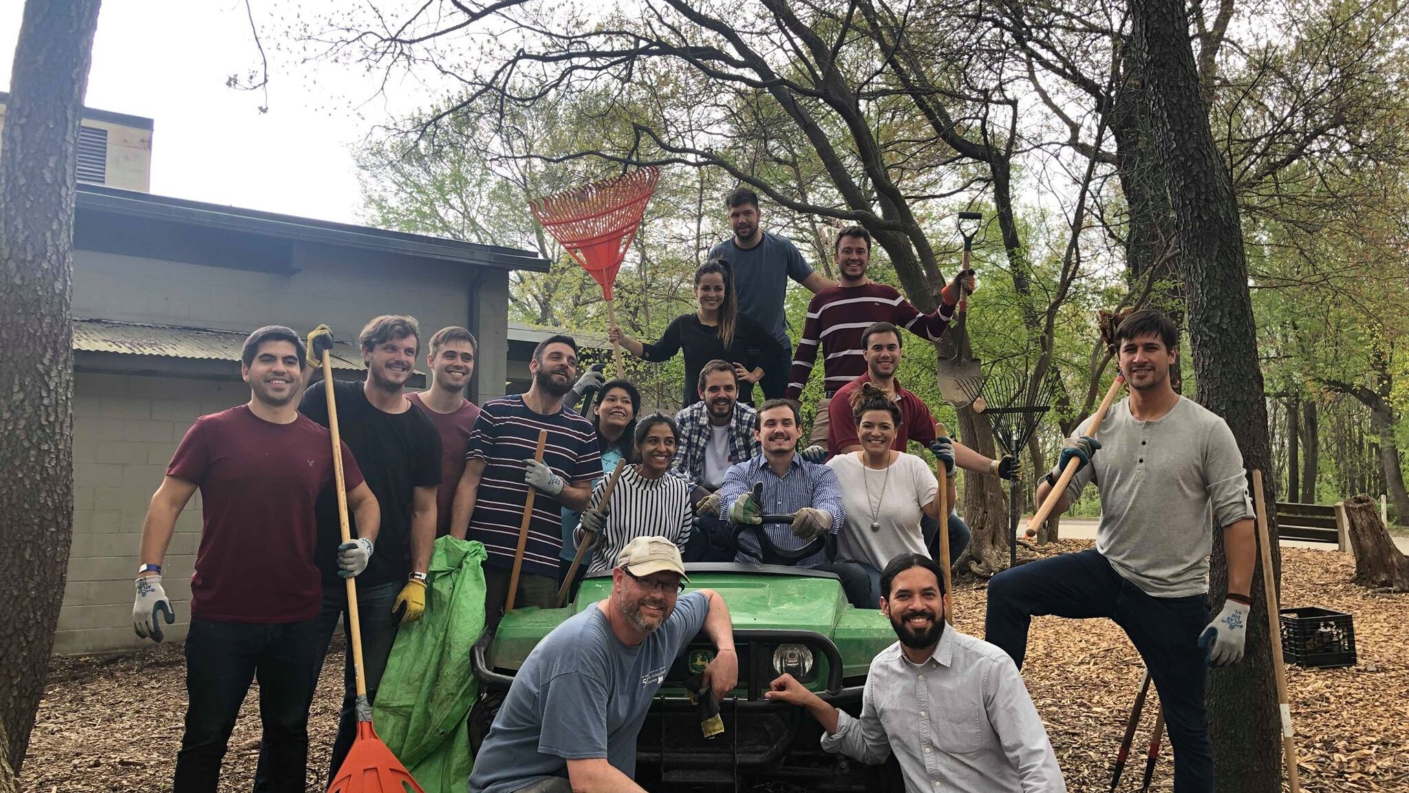 A group of volunteers with rakes stands around a gator at the Schuylkill Center.