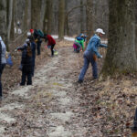 A group of volunteers in winter clothing works along a trail.